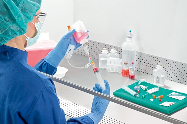 Nurse with syringe and container preparing drugs manually